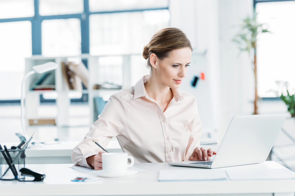 Female thought leader at laptop writing an article.