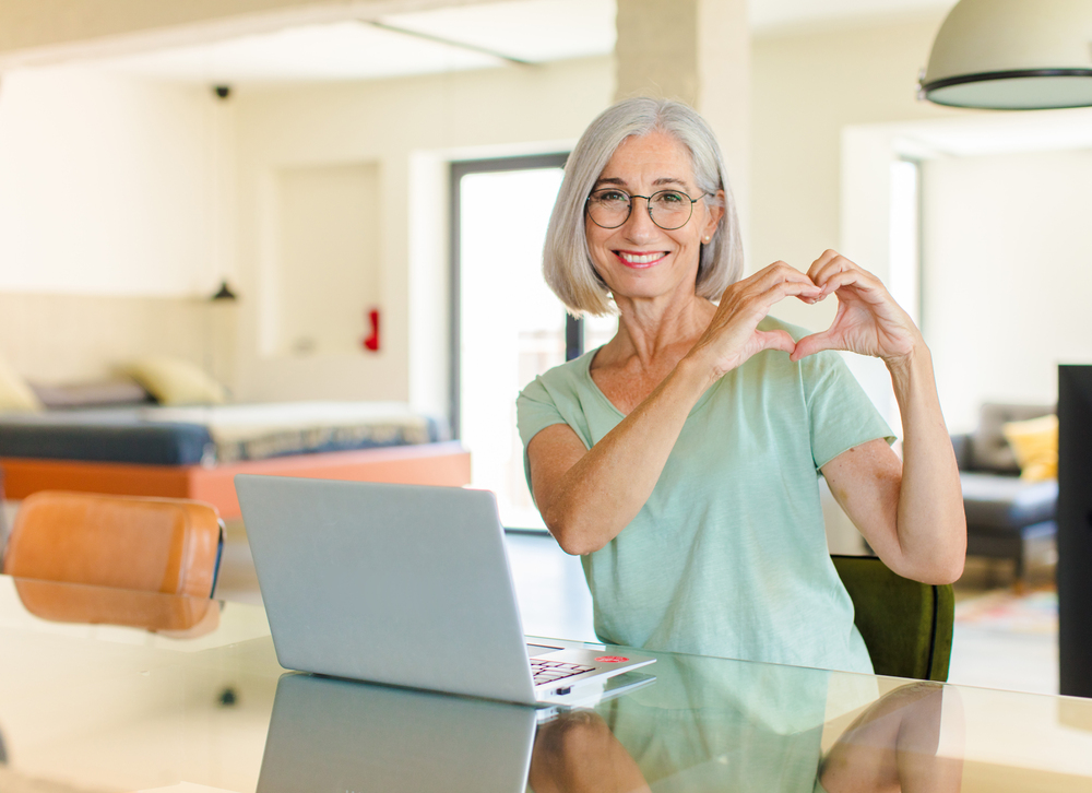 female leader at lap top making a heart shape with her hands