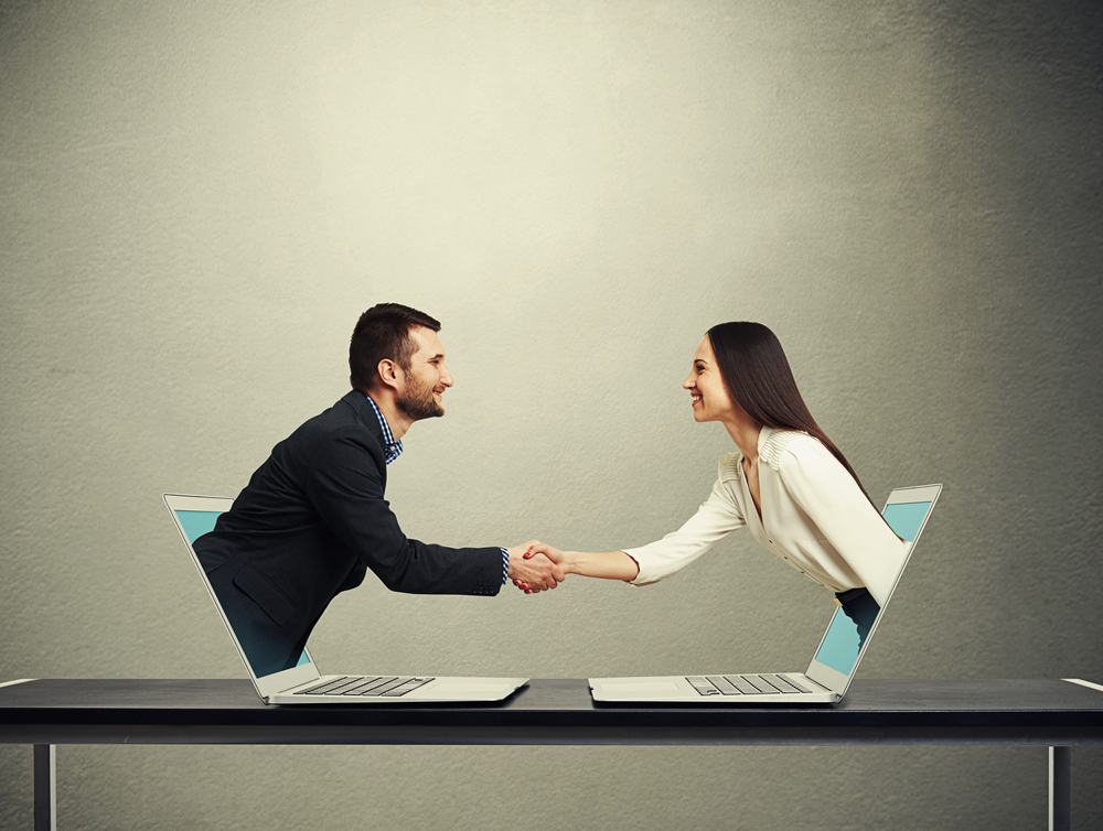 man and woman reaching out of laptop screen shaking hands after reading LinkedIn profile